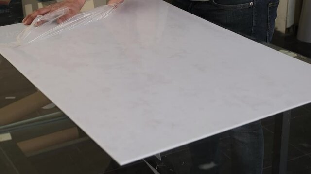Man removing protective gelatin from the surface of white plastic material