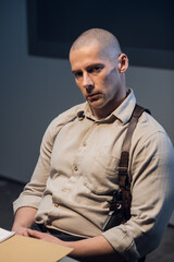 Portrait of a young prospective investigator at work. Strong guy with a shoulder holster. Stern look.