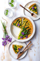 Green asparagus, sweet peas Tart with edible chives flowers or blossoms. Seasonal spring dinner table, overhead view.