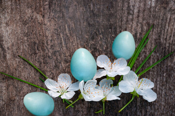 Easter background with colored blue eggs and cherry flowers on a wooden table. Easter concept. Greeting Easter card.