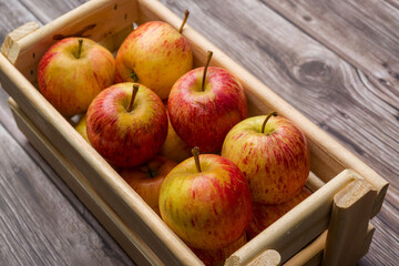Brazilian apples in a wooden box on a wooden table.