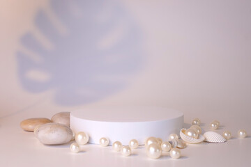 White podium on the white background with pearls and seashells. Podium for product, cosmetic presentation. Creative mock up. Pedestal or platform for beauty products.