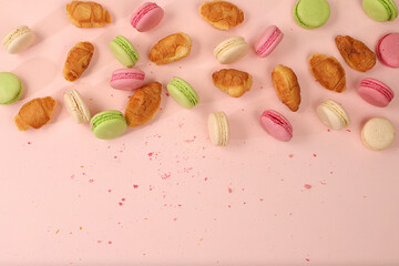 Fresh ruddy and colorful macaroons croissants on a light table with crumbs, Top view, place for text. Modern bakery concept, business card for advertising or invitation. Deliciousl breakfast,