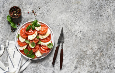 Caprese is a tomato and mozzarella appetizer. Italian salad on the kitchen table with space for the text. View from above.