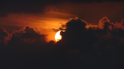 Sunset in the maldives with sun partly covered by clouds