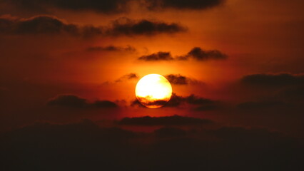 Sunset in the maldives with sun partly covered by clouds