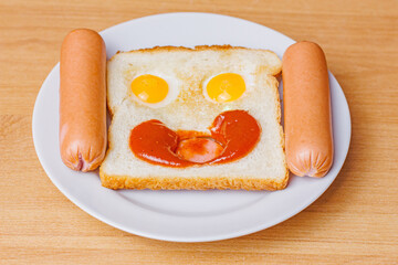 hot toast with eggs, sausages and ketchup for breakfast in the form of a smiling face
