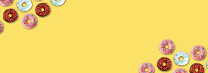 Delicious colorful donuts on yellow background, flat lay. Space for text