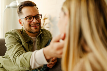 Photo of young beautiful couple embracing on couch at home.