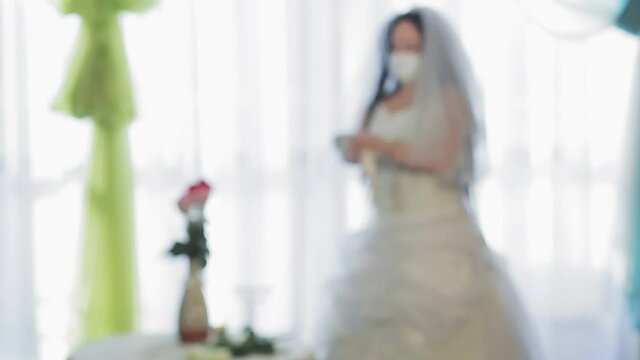 A Jewish bride in a wedding dress and a veil wearing a medical mask puts on elegant white gloves. From blur to sharpness