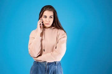 A young girl is talking on the mobile phone. Portrait of emotions. Waiting dial on the phone line,...