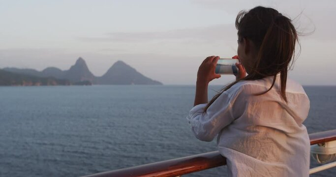 Cruise boat tourist taking mobile phone pictures of Deux pitons peaks, St-Lucia, Caribbean. The Gros and Petit Piton, world heritage site. Woman on ship in Castries, port of call.