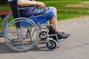 Obraz premium Elderly man with diabetes and kidney disease sitting on wheelchair walking with assistant in the park.