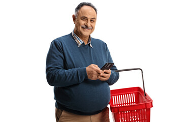 Mature man holding a shopping basket and a mobile phone