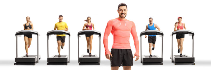 Obraz premium Fit muscular man posing with people running on treadmills in a row in the back