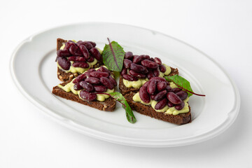 Rye bread bruschetta with vegetarian pate, red beans and greens. Banquet festive dishes. Gourmet restaurant menu. White background.