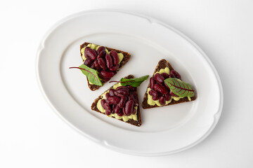 Rye bread bruschetta with vegetarian pate, red beans and greens. Banquet festive dishes. Gourmet restaurant menu. White background.