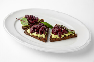 Rye bread bruschetta with vegetarian pate, red beans and greens. Banquet festive dishes. Gourmet restaurant menu. White background.