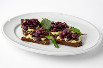 Rye bread bruschetta with vegetarian pate, red beans and greens. Banquet festive dishes. Gourmet restaurant menu. White background.