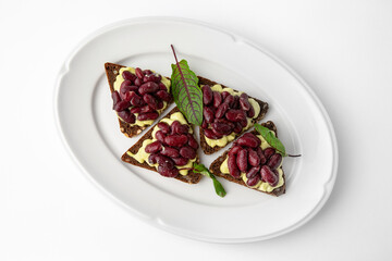 Rye bread bruschetta with vegetarian pate, red beans and greens. Banquet festive dishes. Gourmet restaurant menu. White background.