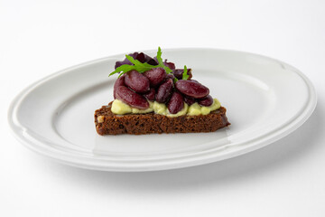 Rye bread bruschetta with vegetarian pate, red beans and greens. Banquet festive dishes. Gourmet restaurant menu. White background.