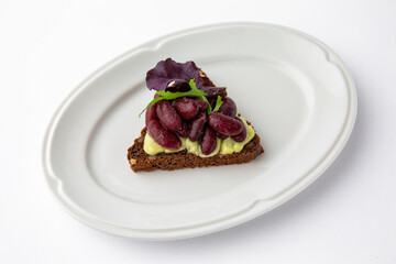 Rye bread bruschetta with vegetarian pate, red beans and greens. Banquet festive dishes. Gourmet restaurant menu. White background.