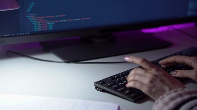 Macro footage of female programmer who is writing new lines of html code by typing on keyboard. A worker of IT support. A woman is developing new software. Office job in sphere of modern technologies.