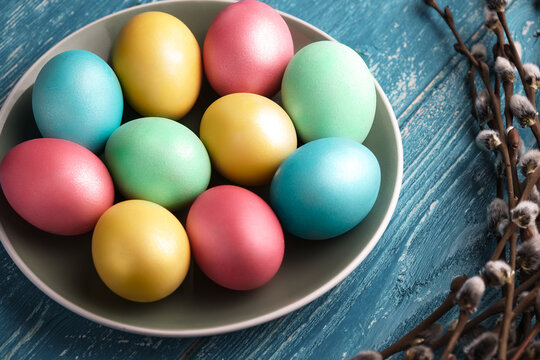 Multicolored painted eggs for easter with pussy willow sprig on wooden background
