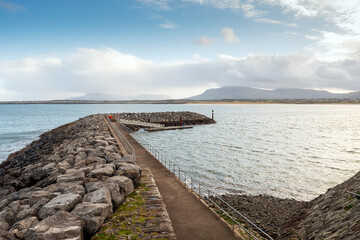 Stone build structure of Mullaghmore harbor. County Sligo, Ireland. Benbulben flat top mountain in the background. Low cloudy sky.