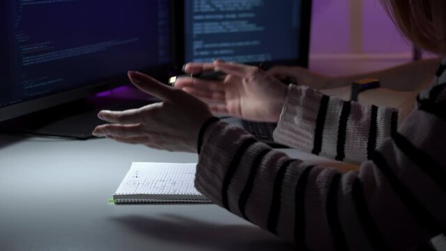 Process of programmers work who are sitting in front of computer and discussing details in closeup. A woman is talking and gesticulating while a man is typing html code on keyboard. Theme of team job.