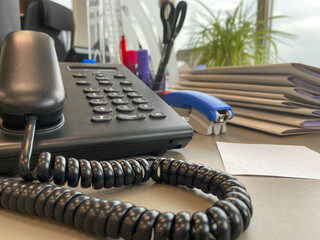 Gray and black business wired phone with receiver, dial and large display in the business office environment