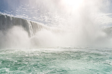 Horseshoe Falls, a part of Niagara Falls, with a sun shining through a tall dense cloud