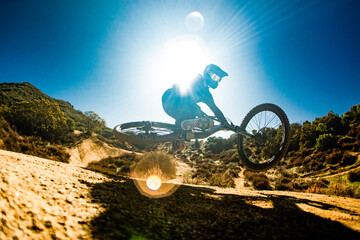 A downhill mountain biker jumps off a dirt trail on a warm summer day in a California