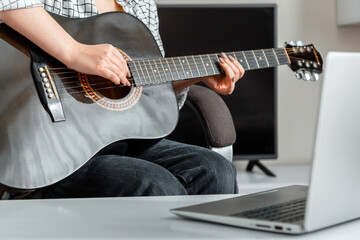 Online musical guitar performance. Young woman plays acoustic guitar at home for online audience on...