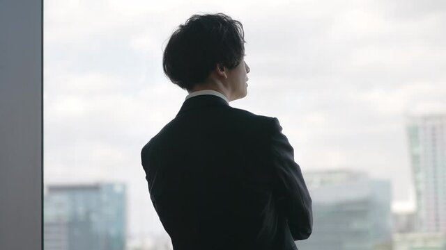 窓の外を眺めるビジネスマン