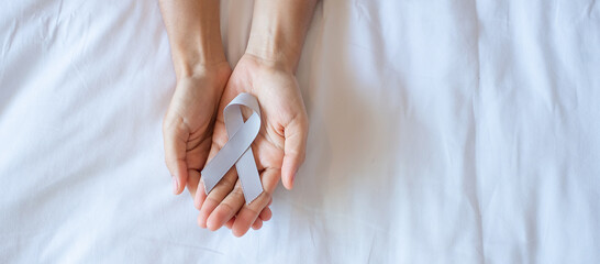 Brain Cancer Awareness month, woman hand holding grey color Ribbon for supporting people living. Healthcare and World cancer day concept