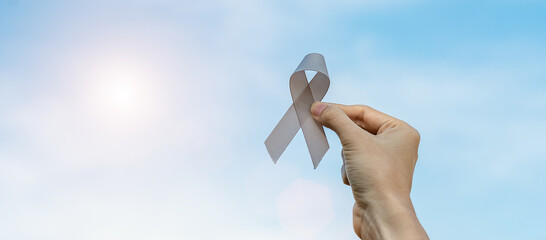 Brain Cancer Awareness month, woman hand holding grey color Ribbon for supporting people living. Healthcare and World cancer day concept
