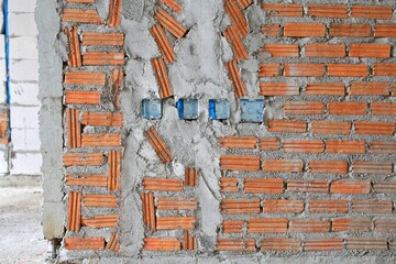 Embedding the electrical box in the brick wall before plastering