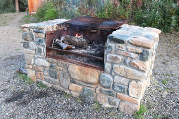 A large stone outdoor grill with a fire burning
