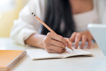 Close up. Woman hand with a pencil taking notes at the office.
