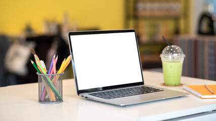 Fototapeta na wymiar Laptop blank white screen with stationary equipment on the desk. Mockup.