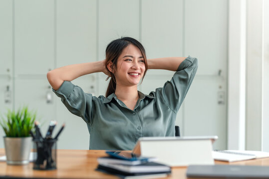 Asian woman enjoy and happy of relaxing at the office. Hold hands behind head concept of success future.