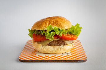 Delicious hamburger on wooden background. Burger with tomato, lettuce, meat and cheese.