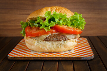 Delicious hamburger on wooden background. Burger with tomato, lettuce, meat and cheese.