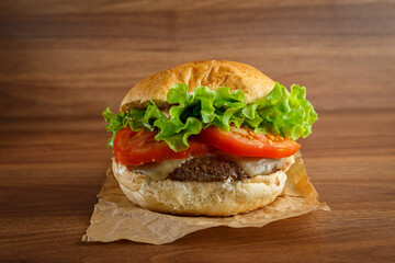 Delicious hamburger on wooden background. Burger with tomato, lettuce, meat and cheese.