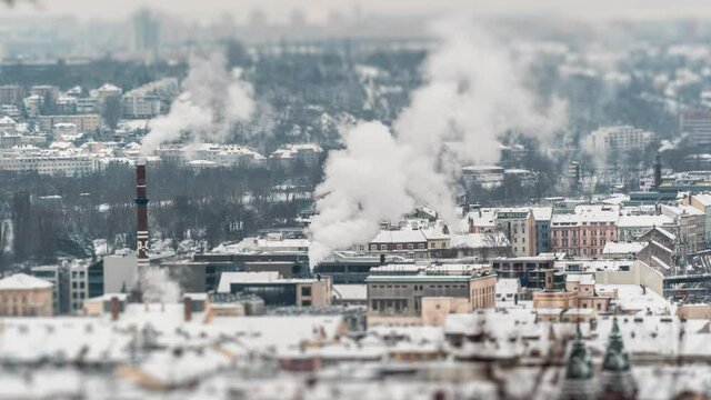 Prague urban landscape. Snow-covered roofs, smoke coming out of the high industrial chimneys. Smog hanging above the city.