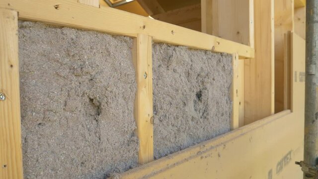 CLOSE UP: Grey ecofriendly cellulose insulation fills up a frame on a wooden wall of CLT house under construction. Detailed shot of modern environmentally friendly housing insulation covering a house.