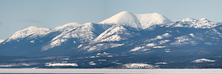 Magnificent winter panorama landscape of northern Canada take in springtime, early April during the start of the frozen river thawing. Towering mountain peaks, snow covered landscape.  Tagish, Yukon