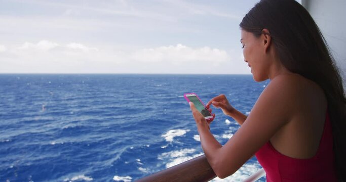 Cruise ship woman using phone on travel vacation at ocean. Asian girl using social media looking at picture on wifi on tropical holidays. Internet on international seas concept. Tourist.