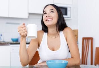 Obraz na płótnie Canvas Portrait of young girl having breakfast in the kitchen